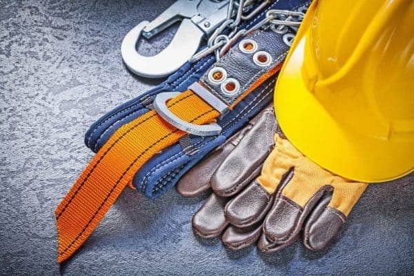 Construction safety harness protective gloves hard hat on black background maintenance concept