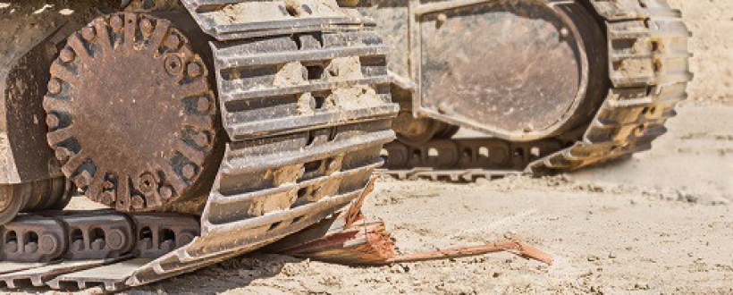 Close up of muddy steel tracks on mini excavator